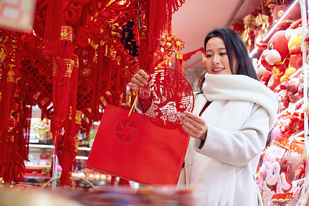 新春集市年货店里挑选窗花的女子背景