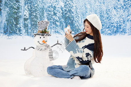 雪地里使用相机的可爱女孩图片