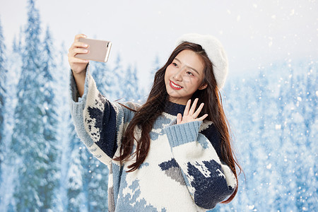 雪地里的甜美美女使用手机自拍图片