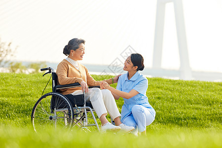 年轻女护工户外照顾轮椅老人图片