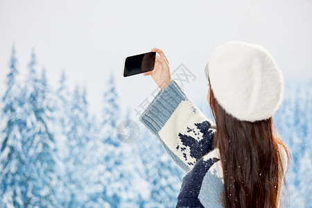 雪地里的美女使用手机自拍背影高清图片