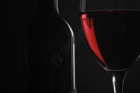 黑色背景中装有红酒和玻璃的瓶子图片