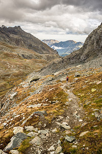 在危险的徒步路上行走的希克人穿过一个陡峭的岩石坡有着广阔的全景和图片