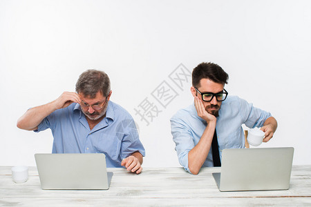 两个同事在白色背景的办公室一起工作两人都在看电脑屏幕负面情绪和图片