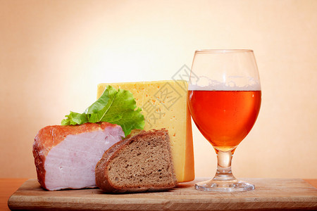一杯啤酒靠近奶酪和肉类与墙图片