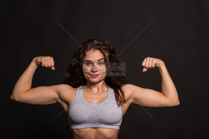 美丽的运动女孩在深色背景上展示身体的肌肉美丽的atletky专业机构体育杂志海报图片