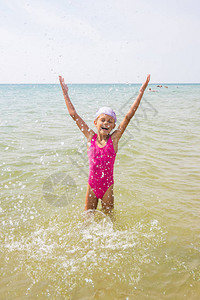 快乐的女孩放开溅水站在海里背景图片