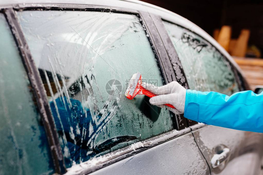 妇女用刮板除冰侧车挡风玻璃冬天的汽车图片