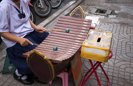 有制服打鼓棍的青年学生在街上敲打xylophone图片