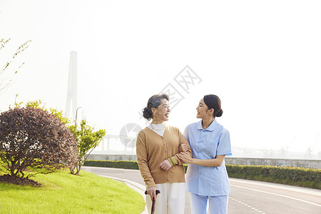 年轻女护工户外照顾老人背景图片