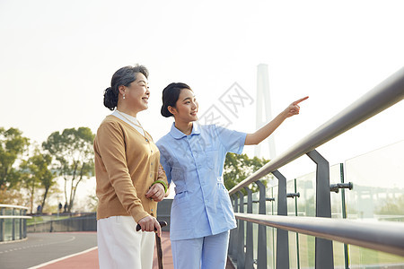 年轻女护工户外陪伴老人散步图片