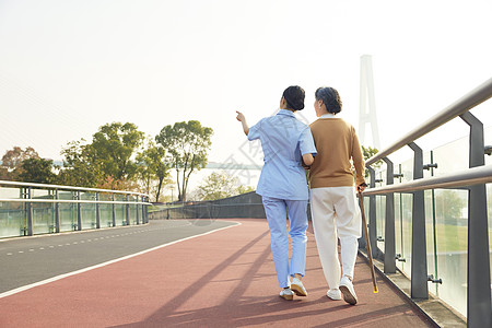 女护工陪伴老人公园散步背影背景