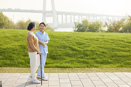 老人陪伴年轻女护工陪伴老人公园散步背景