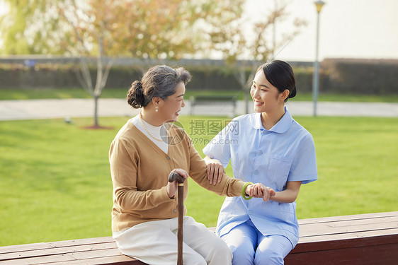 年轻女护工在公园给老人按摩康复图片