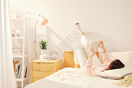 年轻美女卧室躺在床上看书图片