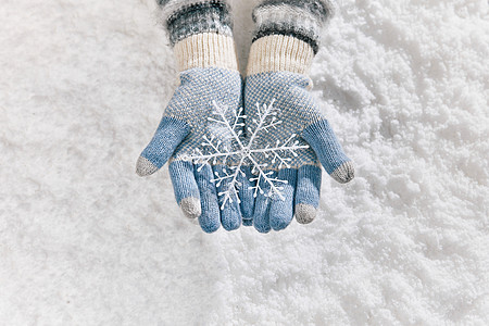 雪地里戴手套手捧雪花片特写背景图片