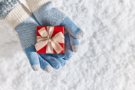 雪地里手捧礼物盒特写图片