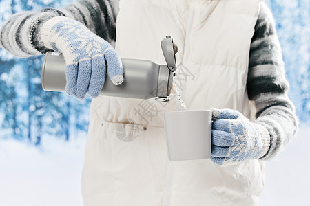 女子使用笔刷雪地里的女子使用保温杯喝水特写背景