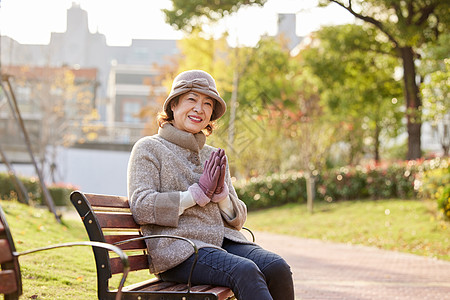 冬季晒太阳中老年妇女坐在公园长椅上休息背景