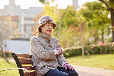 老人散步中老年妇女坐在公园长椅上休息背景