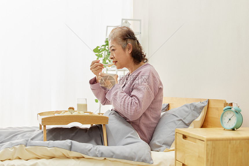 卧床吃早餐喝粥的老人图片