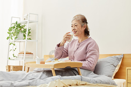 居家老人卧床吃早餐看电视高清图片