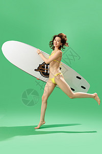 兴奋的青年女人抱着冲浪板奔跑高清图片