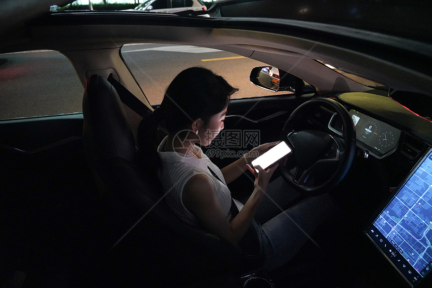 夜晚青年女人坐在汽车里使用手机图片