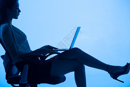 青年女士坐在椅子上使用平板电脑图片