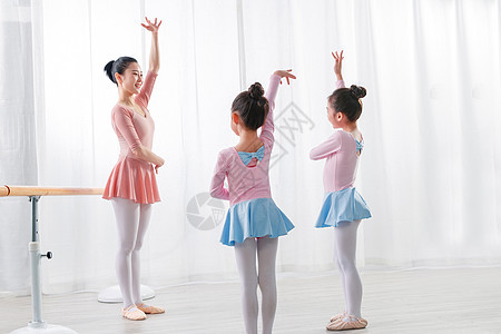 年轻舞蹈老师教小女孩们跳芭蕾图片