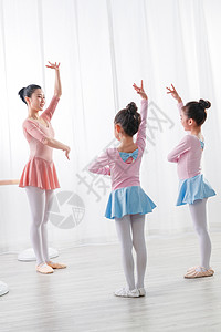 年轻舞蹈老师教小女孩们跳芭蕾图片