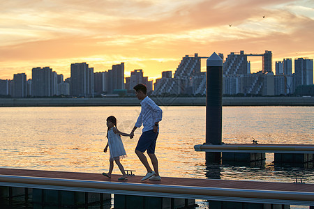 夕阳下父女剪影青年父女在海边玩耍背景