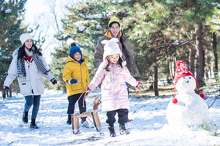 在雪地上玩雪橇的一家人图片