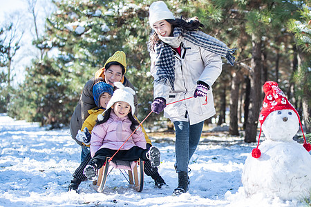 在雪地上玩雪橇的一家人图片