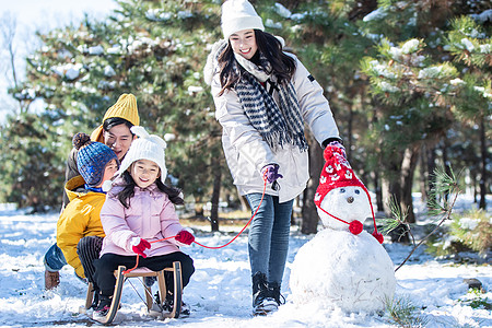 一家人玩雪在雪地上玩雪橇的一家人背景