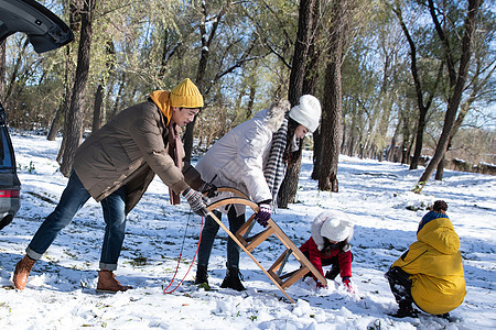 在雪地上准备玩雪橇的一家人图片