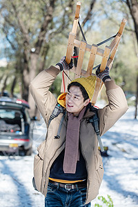 雪地上步行举着雪橇的青年男人图片