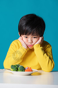 盯着蔬菜发愁的小男孩图片