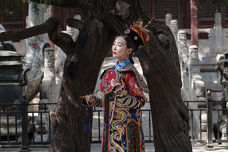 穿清宫服的青年女人站在古树下图片