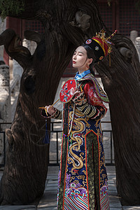 穿清宫服的青年女人站在古树下图片