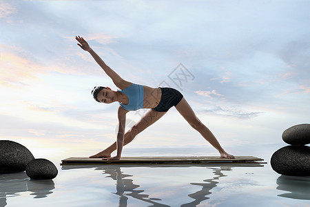 年轻女人在水面上练习瑜伽高清图片
