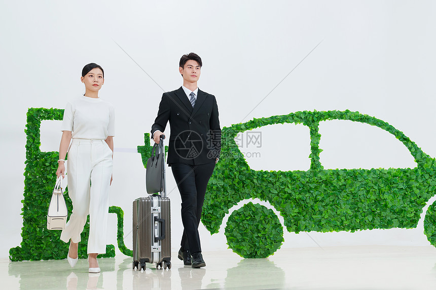 商务人士推着行李箱走在电动汽车旁图片