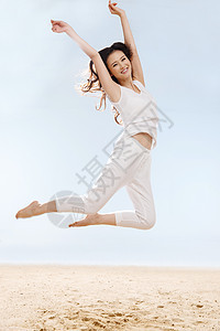 快乐的年轻女在海边跳跃图片
