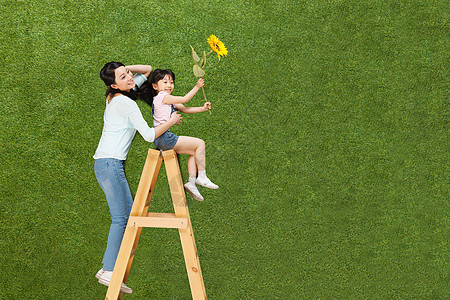 母亲和女儿在草地上拿着向日葵图片