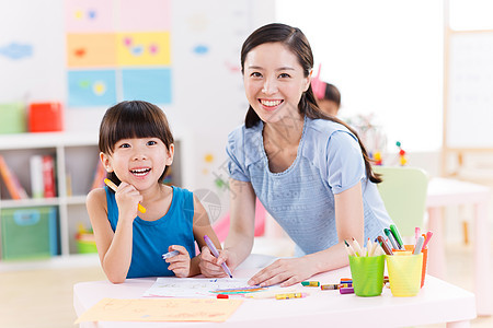 幼儿园里教师在指导女孩作画图片