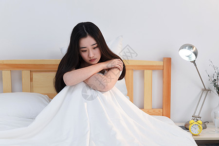 情绪低落的青年女人坐在卧室的床上图片