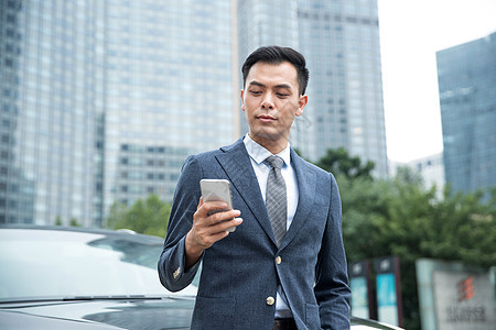 商务男士靠在汽车上使用手机图片