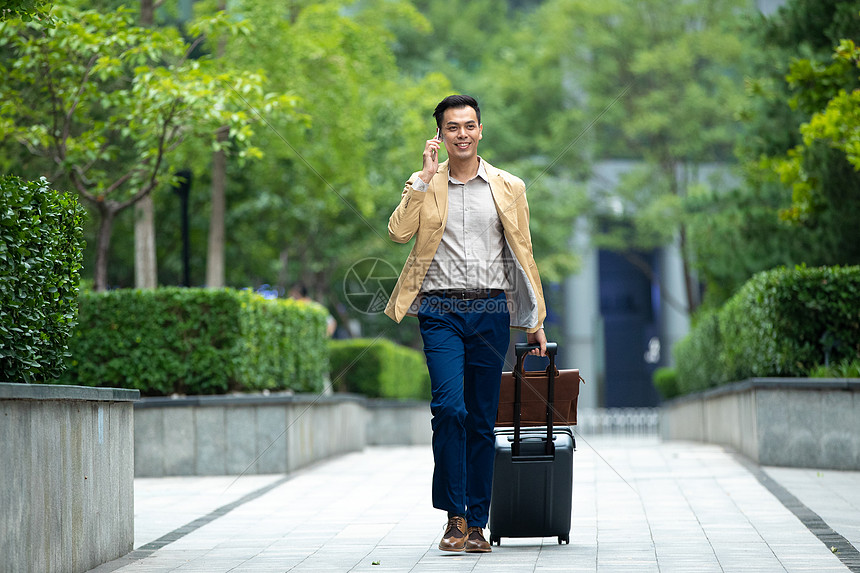 户外拉着行李打电话的商务男子图片