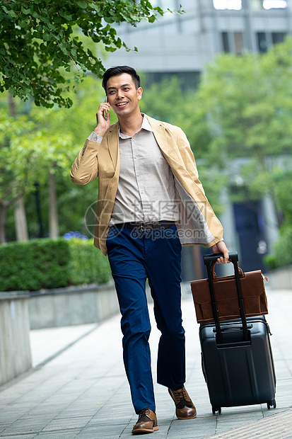 拉着行李打电话的商务男子图片