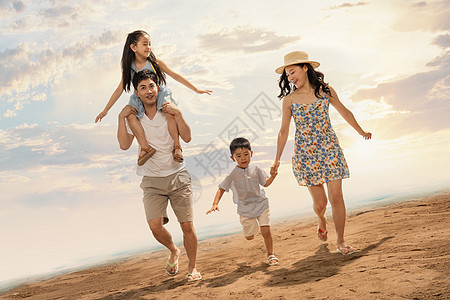 幸福的一家四口在沙滩上奔跑图片